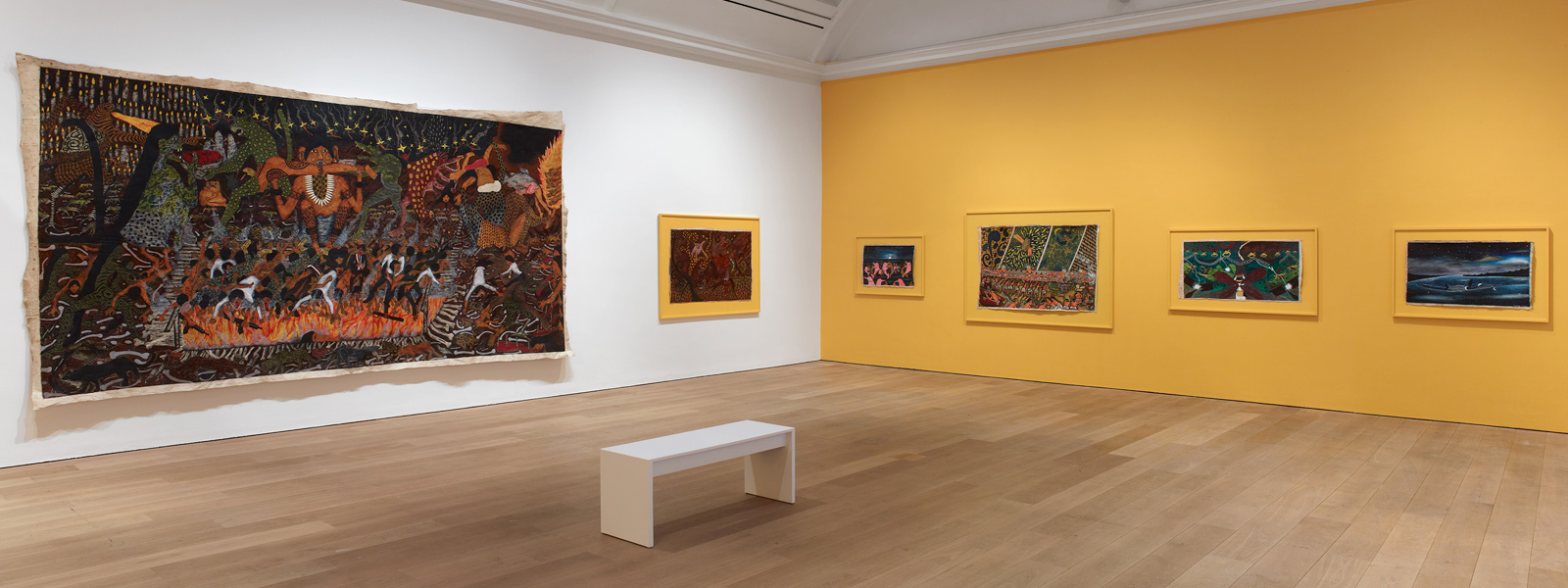A number of paintings hung in an exhibition displayed in a gallery