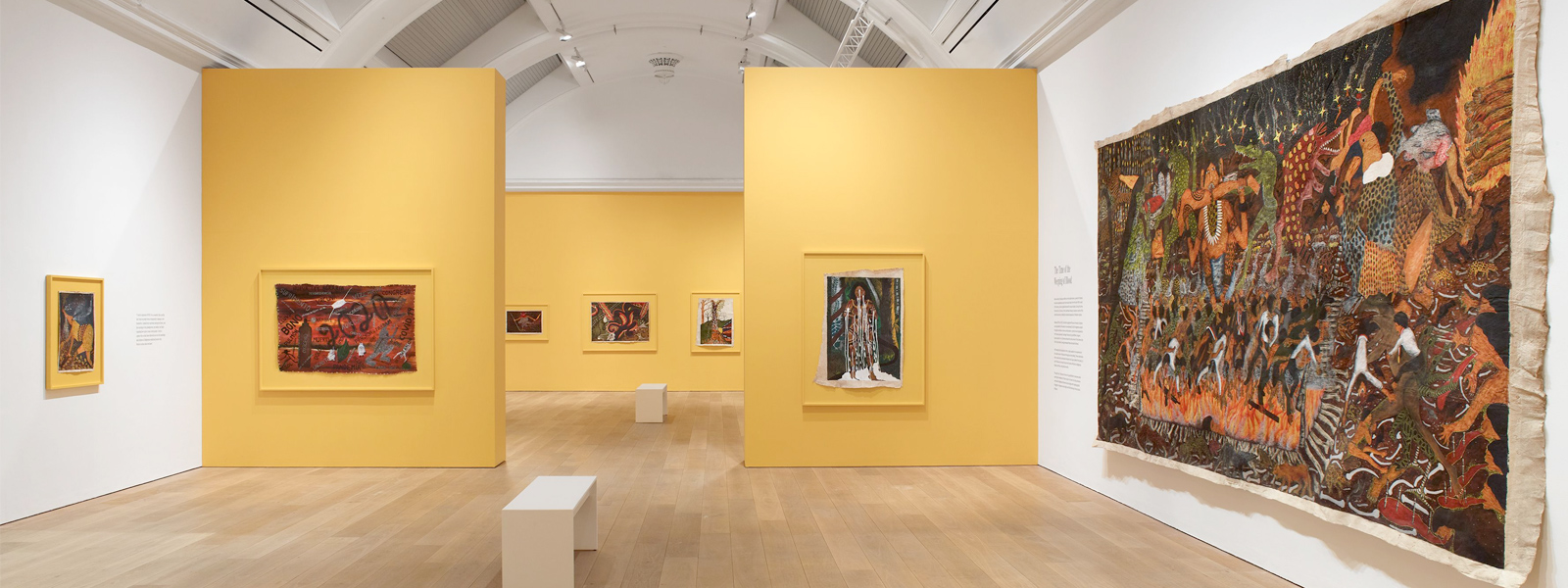 A number of paintings hung in an exhibition displayed in a gallery