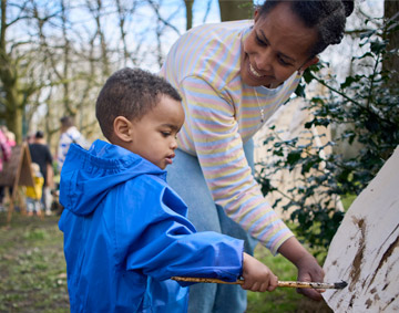 child painting with an adult helping them