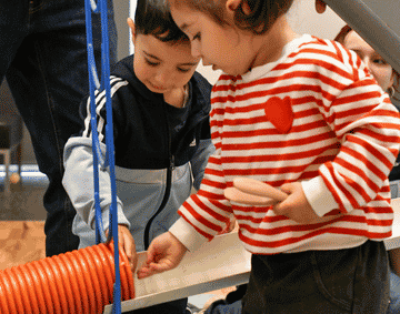 Two children are playing in the gallery with loose parts play