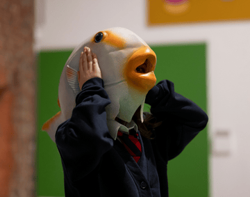 A primary school student wearing a fish mask