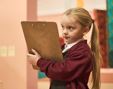 a child with a pencil and paper in a gallery space