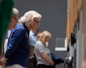 A Visitor Team Assistant and visitors talking about an artwork. 