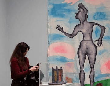 A visitor is stood looking at a display case in Delaine Le Bas: Un-Fair-Ground
