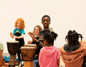 Kids and their parents taking part in a drumming circle. 