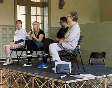 A group of women on stage, talking in a panel format
