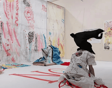 A performer wears a horse's head in a fabric covered gallery space.