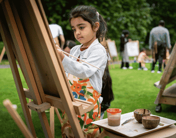 A child painting on a wooden canvas outside