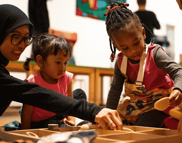 Children and a parent playing with number stones inside a gallery space